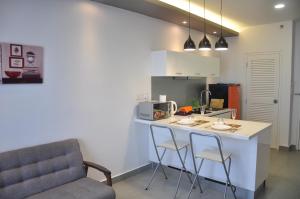 a kitchen with a counter and two chairs and a table at Kanvas Soho by Idealhub in Cyberjaya