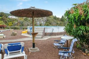 - un groupe de chaises et un parasol à côté de la piscine dans l'établissement Finca La Sorriba, à La Guancha