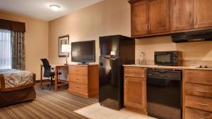 a kitchen with a refrigerator and a desk with a tv at Best Western Plus Seminole Hotel & Suites in Seminole