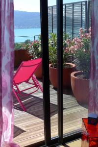 a pink chair sitting on a deck with potted plants at Le Clos Du Lac - location de chambres in Veyrier-du-Lac