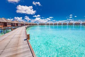 a wooden walkway in the water at a resort at Sun Siyam Olhuveli in South Male Atoll