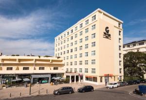 a large white building with cars parked in a parking lot at Vila Galé Estoril in Estoril