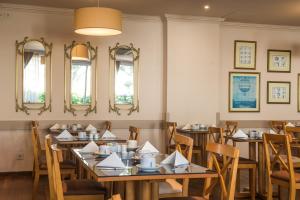 a dining room with tables and chairs and mirrors at Vila Galé Estoril in Estoril
