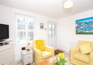 a living room with two chairs and a tv at Lifeboat Cottage in Deal