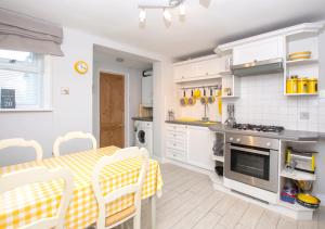 eine Küche mit einem Tisch und eine Küche mit weißen Schränken in der Unterkunft Lifeboat Cottage in Deal
