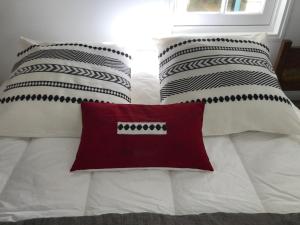uma cama com almofadas pretas e brancas e uma almofada vermelha em La petite Escarpolette em Arzon