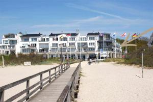 a building on the beach with a boardwalk next to the beach at Villa Meeresrauschen Carpe Diem mit großzügiger Terrasse und extragroßem Strandkorb in Pelzerhaken