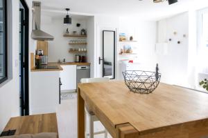 a kitchen with white walls and a wooden table at CITE D'ALETH - Au pied des plages & des ports in Saint Malo