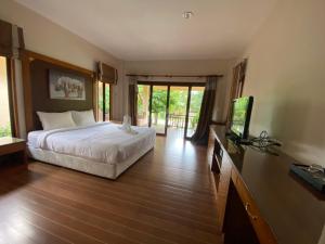 a bedroom with a bed and a flat screen tv at Chaithalay Khanom Resort in Ban Phang Phrao