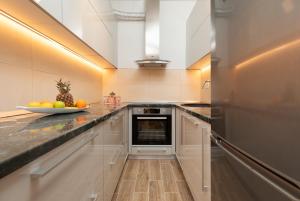 una cocina con armarios blancos y un bol de fruta en la barra en Apartment Olja, en Budva