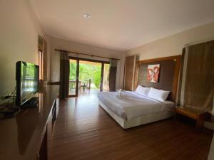 a bedroom with a bed and a flat screen tv at Chaithalay Khanom Resort in Ban Phang Phrao