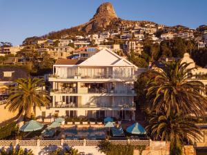 Cape Town的住宿－克拉倫登班特里灣酒店，一座种植了棕榈树和山脉的大型白色建筑