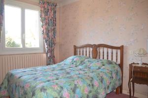 1 Schlafzimmer mit einem Bett mit Blumenbettdecke und einem Fenster in der Unterkunft VILLA AUX PIEDS DES PYRENEES in Azereix