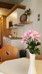 a white vase with pink flowers on a table at Landhotel Böld Oberammergau in Oberammergau