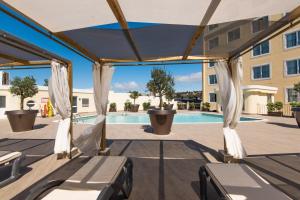 - une terrasse avec des chaises et une piscine dans un bâtiment dans l'établissement Vila Gale Estoril - Adults Friendly, à Estoril