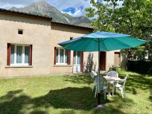 a table and chairs under an umbrella in a yard at Les Gîtes in Jausiers