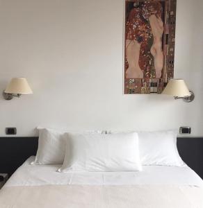 Una cama blanca con dos lámparas y un cuadro encima. en Hotel La Locanda en Cadrezzate