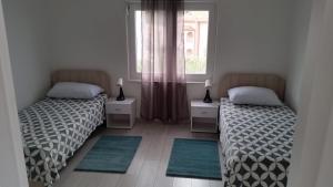 two beds in a room with a window and rugs at Big Blue - Xenija (Veliko Plavetnilo - Ksenija) in Metajna
