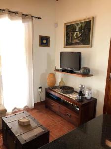 a living room with a tv and a table at Casa da Rainha Bungallow in Estreito da Calheta