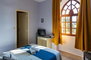 a bedroom with a bed and a window and a desk at Hôtel-Restaurant Le Prieuré devient la "Maison du Prieuré" in Vignoux-sur-Barangeon