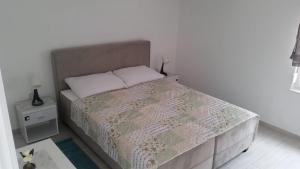 a small bedroom with a bed with a quilt and a night stand at Big Blue - Xenija (Veliko Plavetnilo - Ksenija) in Metajna