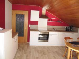 una cocina con armarios blancos y una pared roja en Ferienwohnung Kreuzer Lydia en Furth im Wald