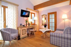 a living room with two couches and a tv at Landhotel Böld Oberammergau in Oberammergau