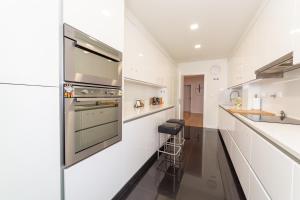 a kitchen with white cabinets and a stainless steel oven at Industrial Lisbon Apartment in Lisbon