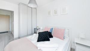 克拉科夫的住宿－Apartamenty Sun & Snow Konopnicka City，白色的床和粉红色及黑色枕头