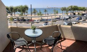 un tavolo e sedie su un balcone con vista sulla spiaggia di Rhode 1b a Roses