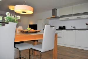 una cucina con tavolo in legno e armadietti bianchi di Hotel & Chalets Herrihof a Todtnauberg