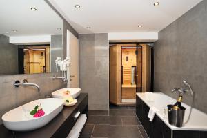 a bathroom with a tub, sink and mirror at Landhotel Böld Oberammergau in Oberammergau
