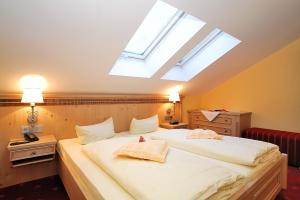 um quarto com uma grande cama branca e uma clarabóia em Landhotel Böld Oberammergau em Oberammergau