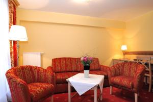 a living room with two chairs and a couch and a table at Landhotel Böld Oberammergau in Oberammergau