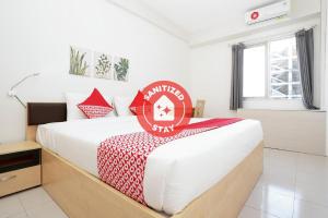 a bed room with a white bedspread and a red bedspread at Vaccinated Staff - OYO Flagship 910 Menara Rungkut Surabaya in Surabaya