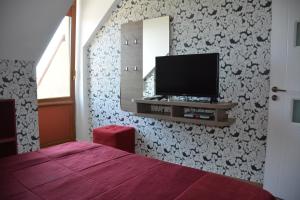 a bedroom with a bed and a tv on a wall at Complex Chayka Guest House in Byala