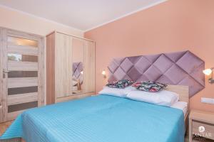sypialnia z niebieskim łóżkiem z fioletowym zagłówkiem w obiekcie Wyspa Solna City Center by Jantar Apartamenty Kołobrzeg w Kołobrzegu