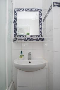 a white bathroom with a sink and a mirror at LOVELY ONE BEDROOM APARTMENT in Nové Zámky