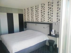 a bedroom with a white bed and a black and white wall at Hôtel Le Nautic in Arcachon