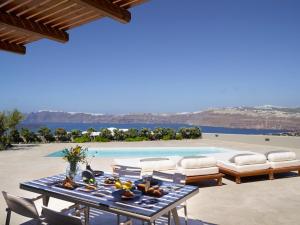 eine Terrasse mit einem Tisch, Stühlen und einem Pool in der Unterkunft Melidonia Suites in Akrotiri