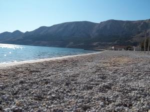 a rocky beach with water and mountains in the background at Lovrić Apartments in Baška