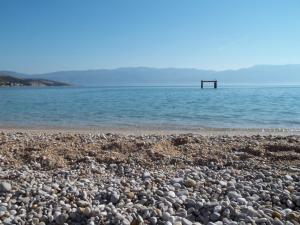 a rocky beach with a pier in the water at Lovrić Apartments in Baška