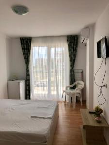 a bedroom with a bed and a chair and a window at Vila Bordei Verde in Mamaia Sat/Năvodari