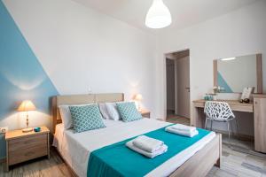 una camera da letto con letto con lenzuola blu e scrivania di Magnolia Rooms a Benitses