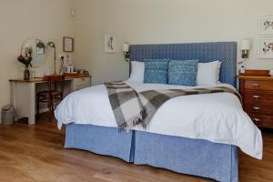 a bedroom with a blue and white bed and a desk at Cornerstone Manor in Grahamstown