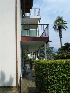 a building with a balcony and a palm tree at Casa La Berika in Orselina