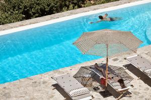 a person laying in a chair under an umbrella next to a swimming pool at Villa Monadi in Kanala
