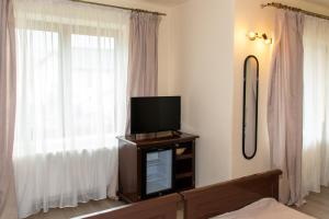 a tv sitting on a stand in front of a window at Pensiunea Sanziana in Gura Rîului