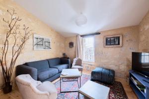 a living room with a blue couch and a tv at Elégant appartement tout confort avec climatisation dans le centre historique de ST Emilion in Saint-Émilion