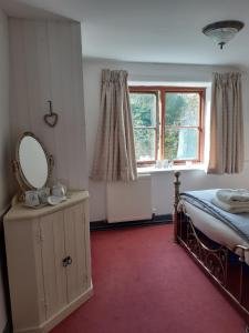 a bedroom with a bed and a mirror and a window at Witherhill Granary in High Bickington
